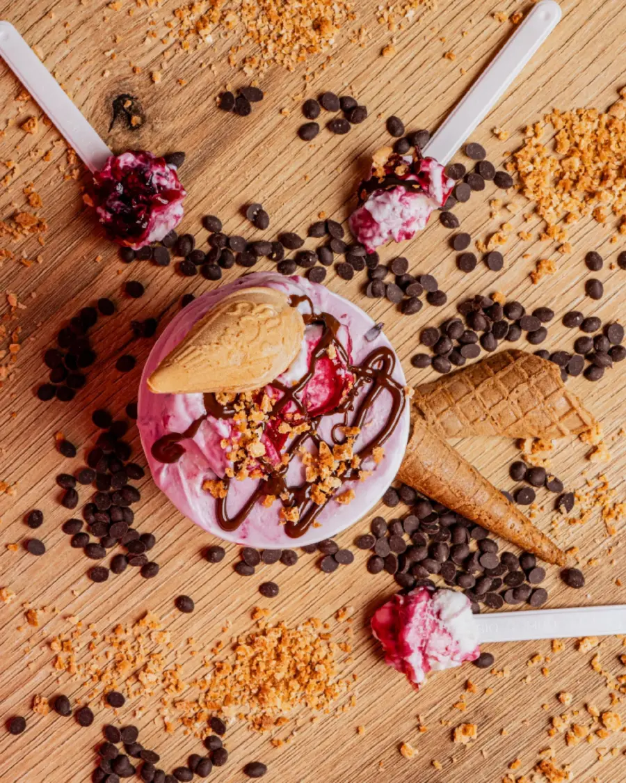 Coppa di gelato vista dall'alto con cono, topping e gocce di cioccolato